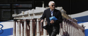 A man crosses a road in front of a bus bearing a picture of the temple of Parthenon in central Athens October 8, 2013. Greece will emerge from six years of recession next year, a draft budget forecast on Monday, signalling the country is past the worst of a crippling debt crisis that nearly broke Europe's single currency. REUTERS/John Kolesidis (GREECE - Tags: POLITICS BUSINESS SOCIETY)