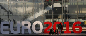 People stand in front of a sign announcing the UEFA Euro 2016 tournament near the Lille Europe railway station in Lille, France, March 12 , 2016. France will host the Euro 2016 soccer tournament from June 10 to July 10. REUTERS/Pascal Rossignol