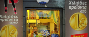 A man speaks on his mobile phone inside a discount shop that shows euro coins on the outside with slogans reading in Greek "Thousands of products from a euro," in Monastiraki in central Athens, Wednesday, June 24, 2015. Prime Minister Alexis Tsipras has arrived in Brussels to meet with the heads of the International Monetary Fund, the European Central Bank and the European Union's executive Commission, the meeting is meant to smooth over some differences on the reforms that Greece proposed to creditors in exchange for rescue loans that it needs to not default on a debt payment June 30. (AP Photo/Petros Karadjias)