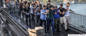People apprehend a Turkish soldier, third right in blue, that participated in the attempted coup, on Istanbul's Bosporus Bridge, Saturday, July 16, 2016. Turkish President Recep Tayyip Erdogan told the nation Saturday that his government was working to crush a coup attempt after a night of explosions, air battles and gunfire across the capital that left dozens dead and scores wounded. Government officials said the coup appeared to have failed as Turks took to the streets overnight to confront troops attempting to take over the country. (AP Photo/Selcuk Samiloglu)