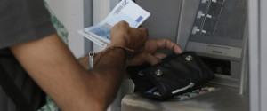 A man uses an ATM of a bank after the government's decision last week to limit daily cash withdrawals to 60 euro ($66) in Athens, Tuesday, July 7, 2015. Greek Prime Minister Alexis Tsipras was heading Tuesday to Brussels for an emergency meeting of eurozone leaders, where he will try to use a resounding referendum victory to eke out concessions from European creditors over a bailout for the crisis-ridden country. (AP Photo/Petr David Josek)