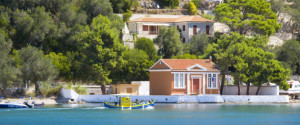 View across the clear turquoise waters of Lakka Bay, fishing boat returning to port, Lakka, Paxos (aka Paxi), Corfu (aka Kerkyra, Kerkira), Ionian Islands, Greece, Europe.