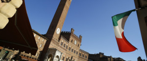 The Italian national flag flies in an entrance to the Piazza del Campo with the Torre del Mangia in the distance, in Siena, Italy, on Friday, Aug. 5, 2016. Banca Monte dei Paschi di Siena SpA's plan to offload $31 billion in doubtful loans, designed to attract investors to a share sale by reducing the bank's risk of losses, will still leave it with a bad-debt level considered unsafe by industry standards. Photographer: Marc Hill/Bloomberg via Getty Images